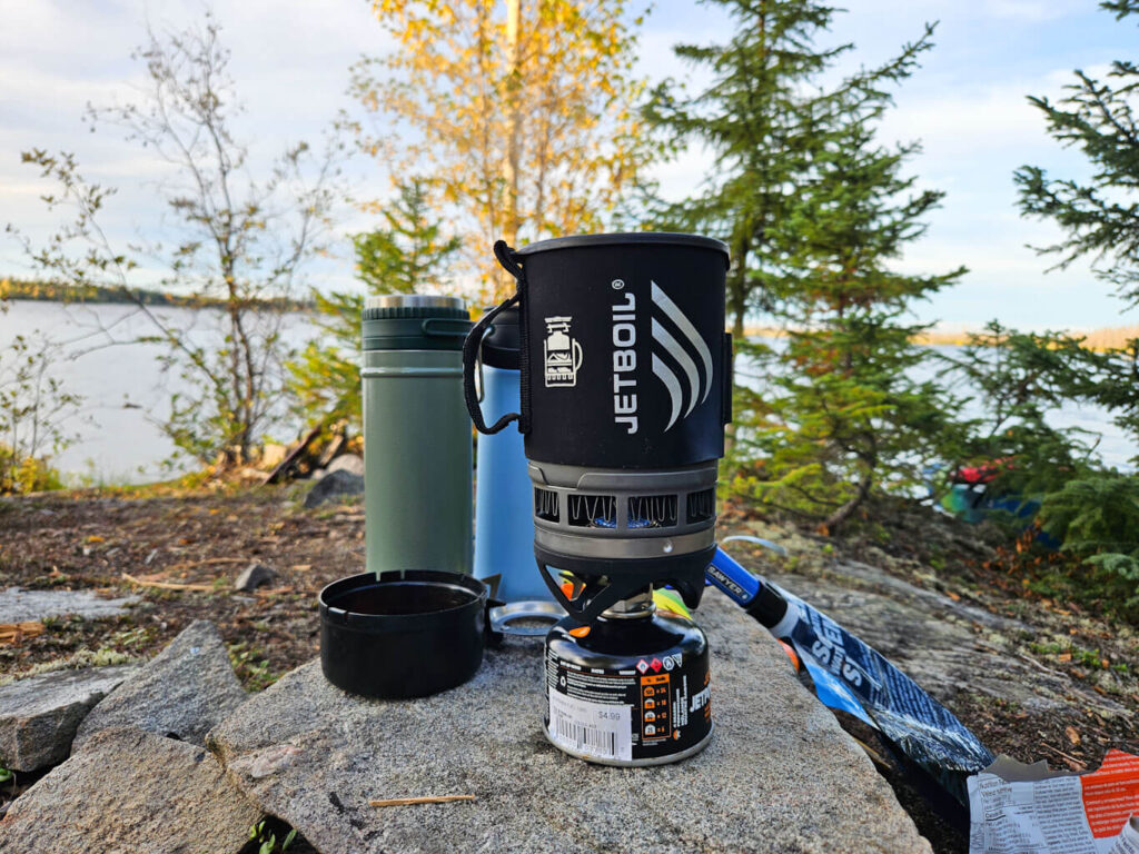 A Jetboil Zip sits on a rock by a lake
